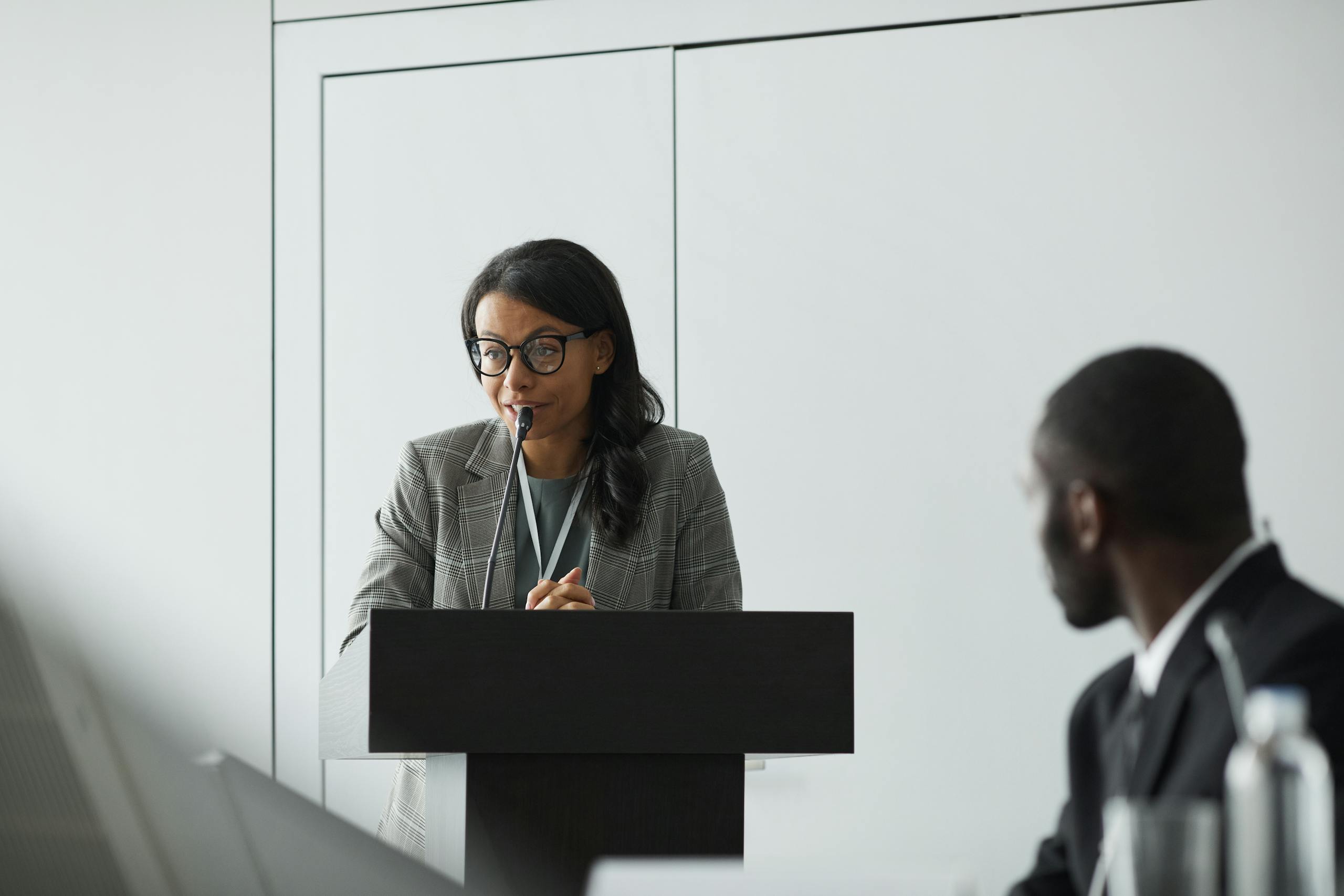 Woman Wearing Eyeglasses Talking Behind a Podium